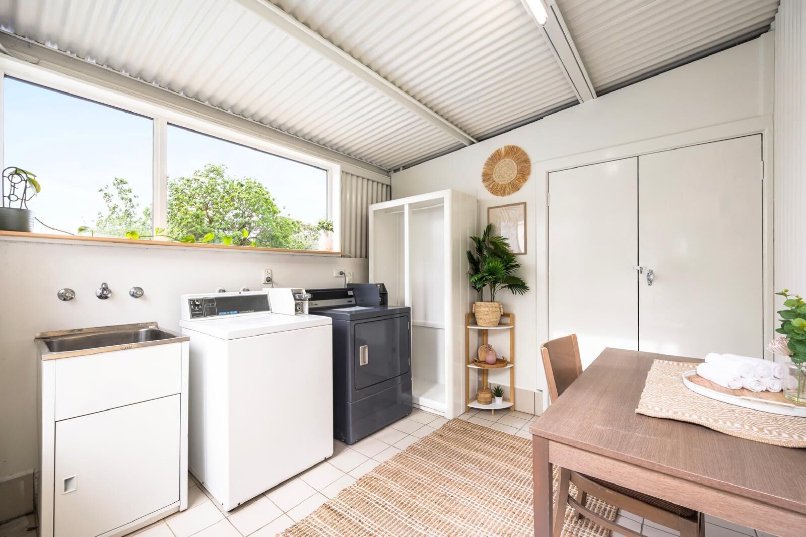 A compact kitchen with a washing machine, a sink, and a dining area with a table and chairs.