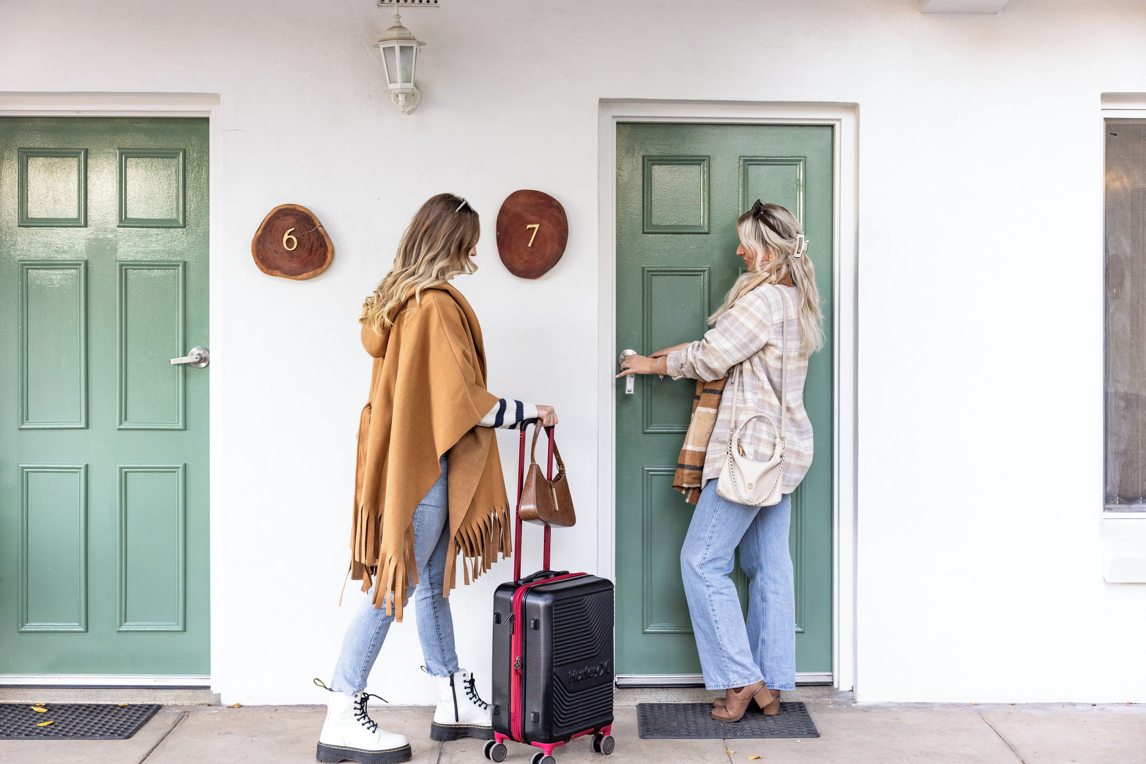 Two women approaching a green door with numbers 6 and 7 on it.