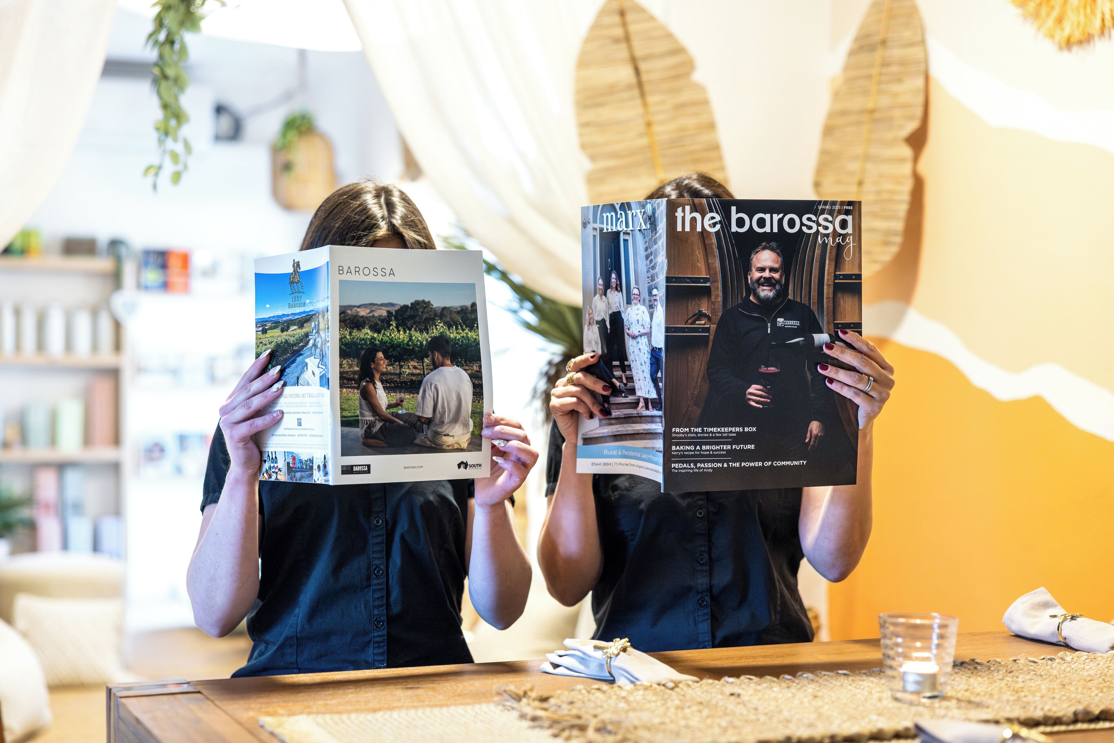 Two individuals holding a magazine with the title 'the barossa' and a logo that reads 'BAROSSA'.