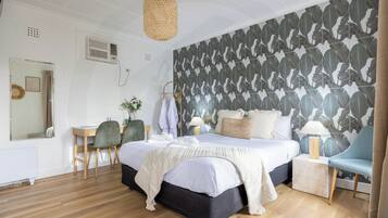 A bedroom with a large bed, a desk, a chair, and a wall with a leaf pattern.