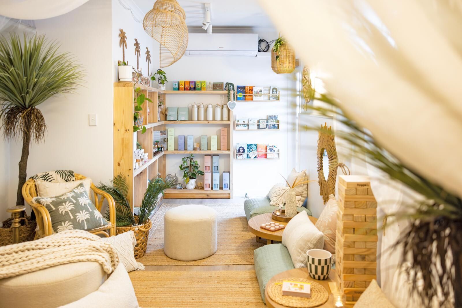 A cozy living room with a sofa, ottoman, and a bookshelf filled with books and decorative items.