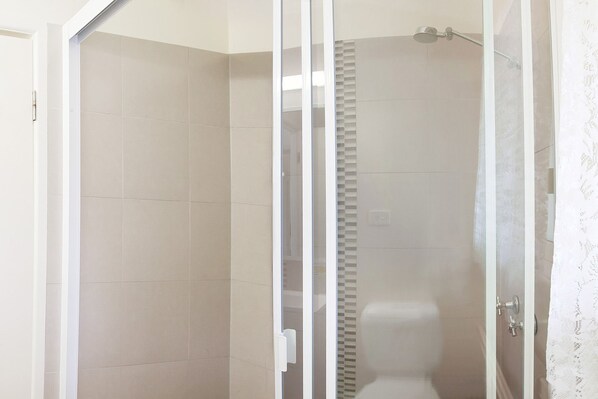 Une salle de bain moderne dotée d’une douche à parois de verre, de toilettes et d’un lavabo.