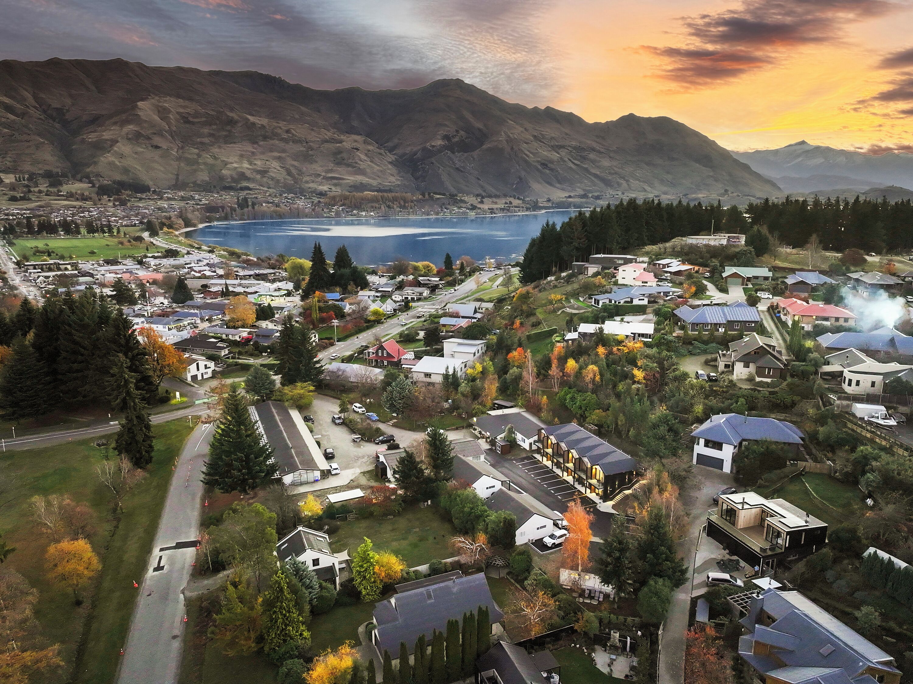 An aerial view of a town with houses, roads, and mountains in the background.