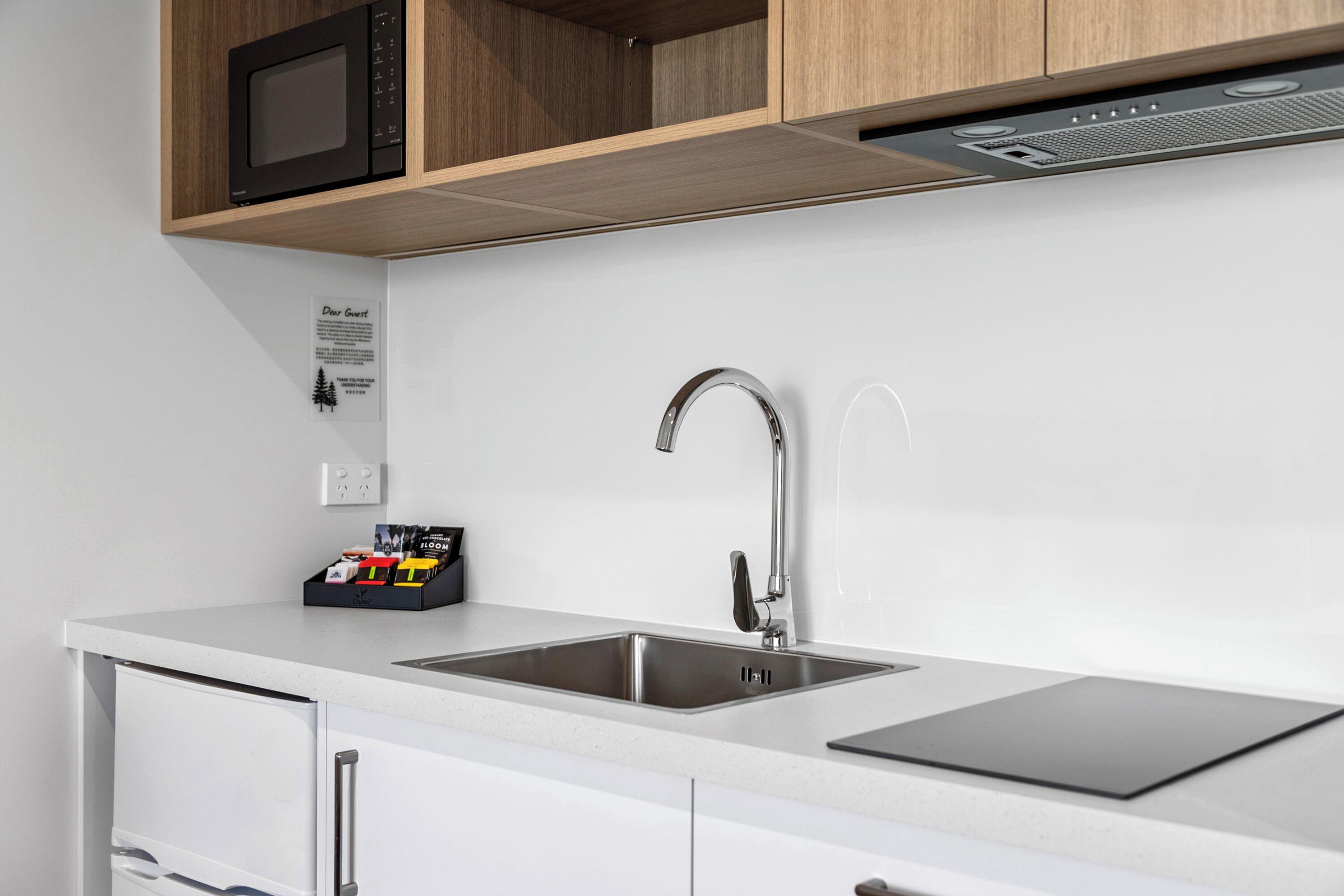 A modern kitchen with a stainless steel sink, wooden cabinets, and a microwave.