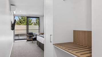 A modern bedroom with a bed, a chair, a TV, and a balcony with a view.