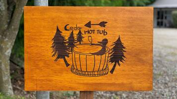 Een houten bord met een afbeelding van een hottub en de tekst 'Cedar Hot Tub'.