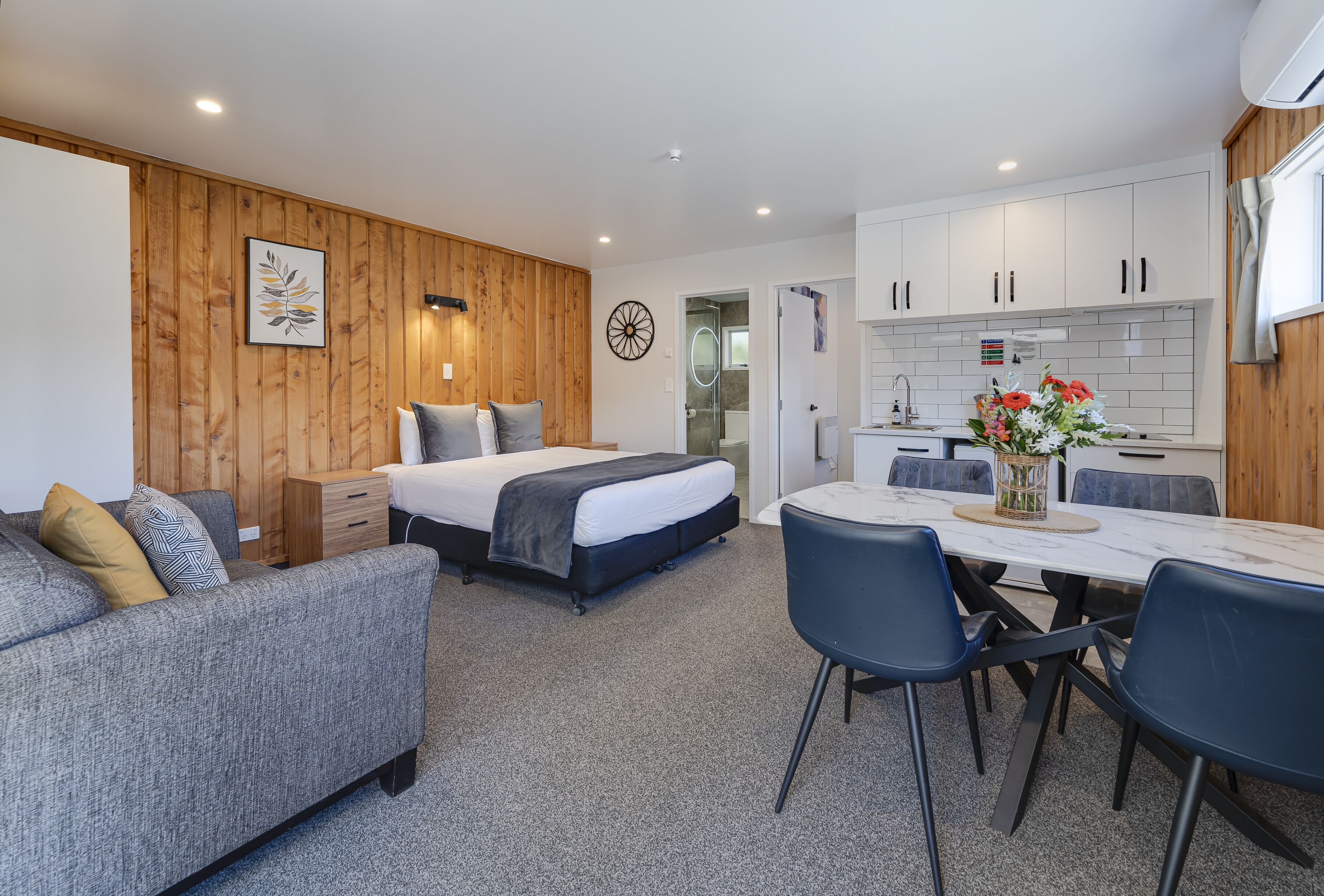 A modern bedroom with a bed, bedside tables, and a small seating area.