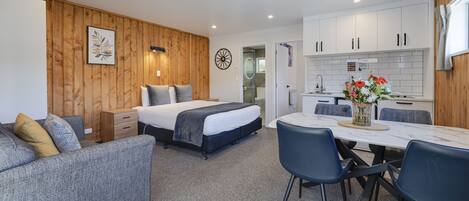 A modern bedroom with a bed, bedside tables, and a small seating area.