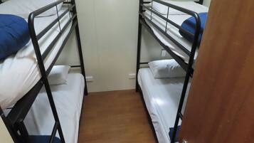 A room with two bunk beds, each with a pillow and a blanket.