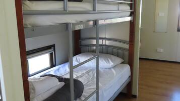 Habitación con literas de dos niveles, suelo de madera y una puerta al fondo.