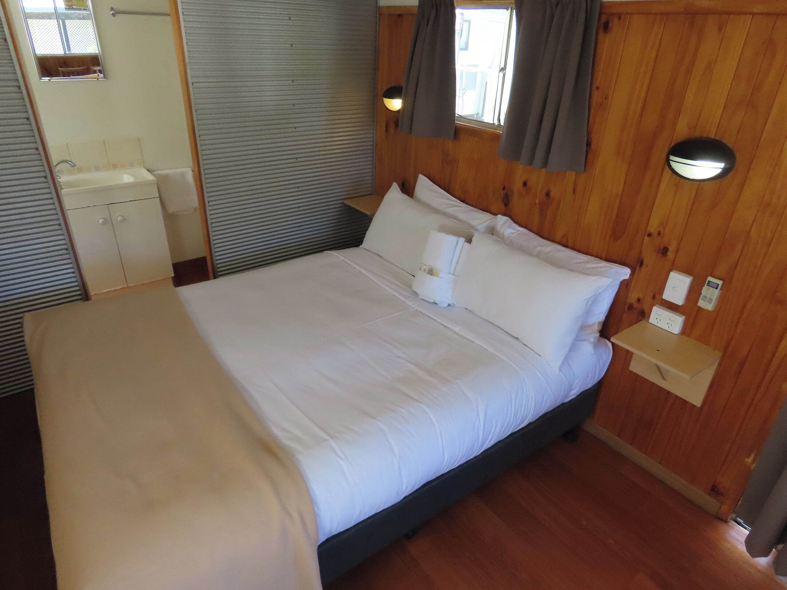 Une chambre à coucher avec un lit, une table de chevet et une petite fenêtre avec des rideaux.