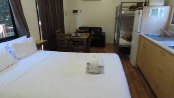 A hotel room with a bed, a desk, a chair, a bunk bed, and a kitchenette.