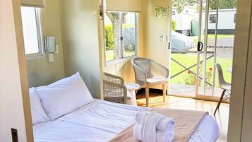 Una habitación de hotel con una cama, ventana, silla y mesa.