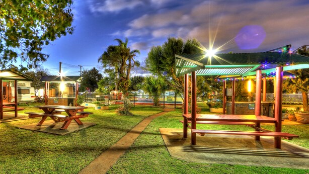 An outdoor park area with picnic tables and a covered seating area, surrounded by greenery and a clear sky. - BIG4 Toowoomba Holiday Park (Harristown)