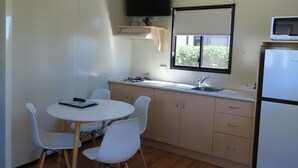 A compact kitchen with a round table and four chairs, a microwave, and a refrigerator. - BIG4 Toowoomba Holiday Park (Harristown)