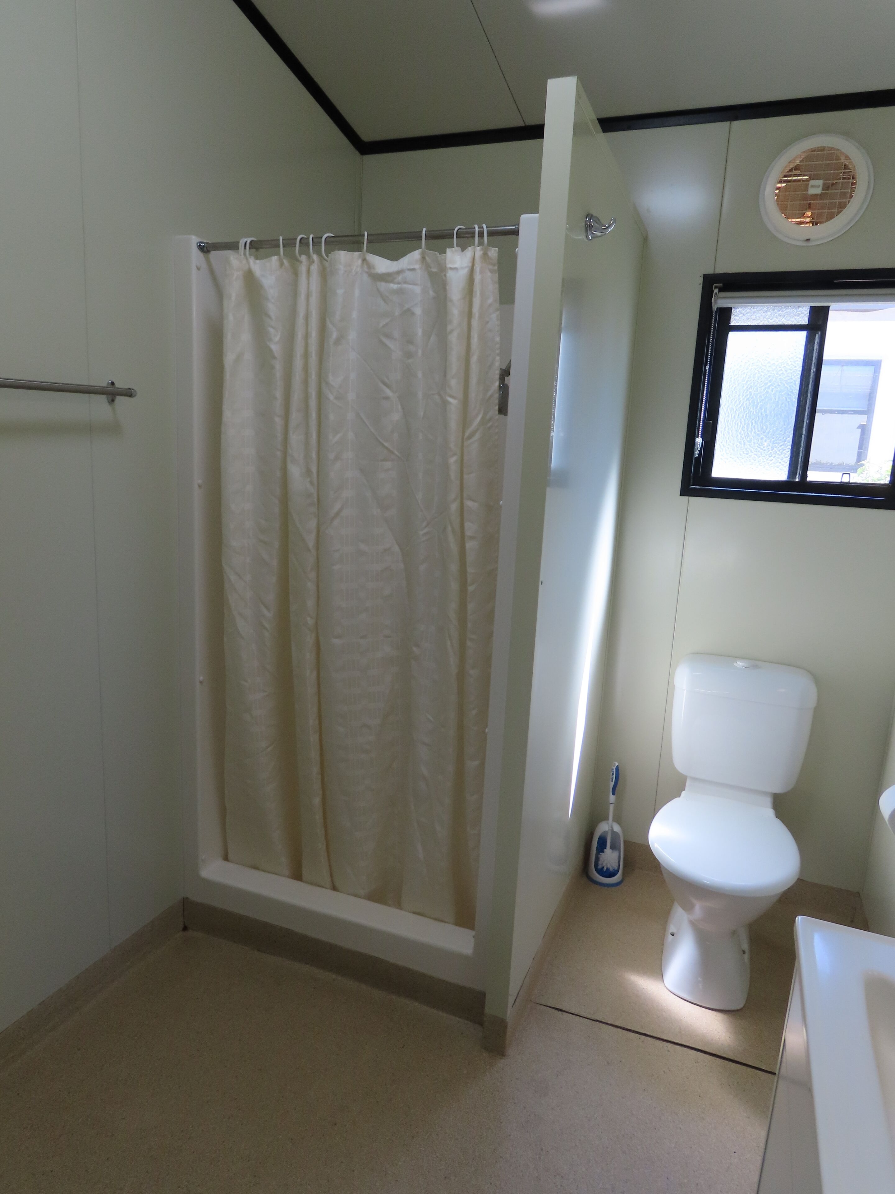Un baño con cortina de ducha, inodoro y ventana.