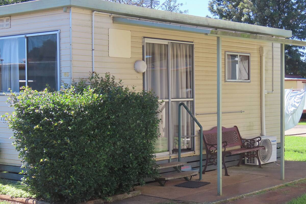 Une maison mobile dotée d’une véranda, d’un banc et d’un ventilateur.