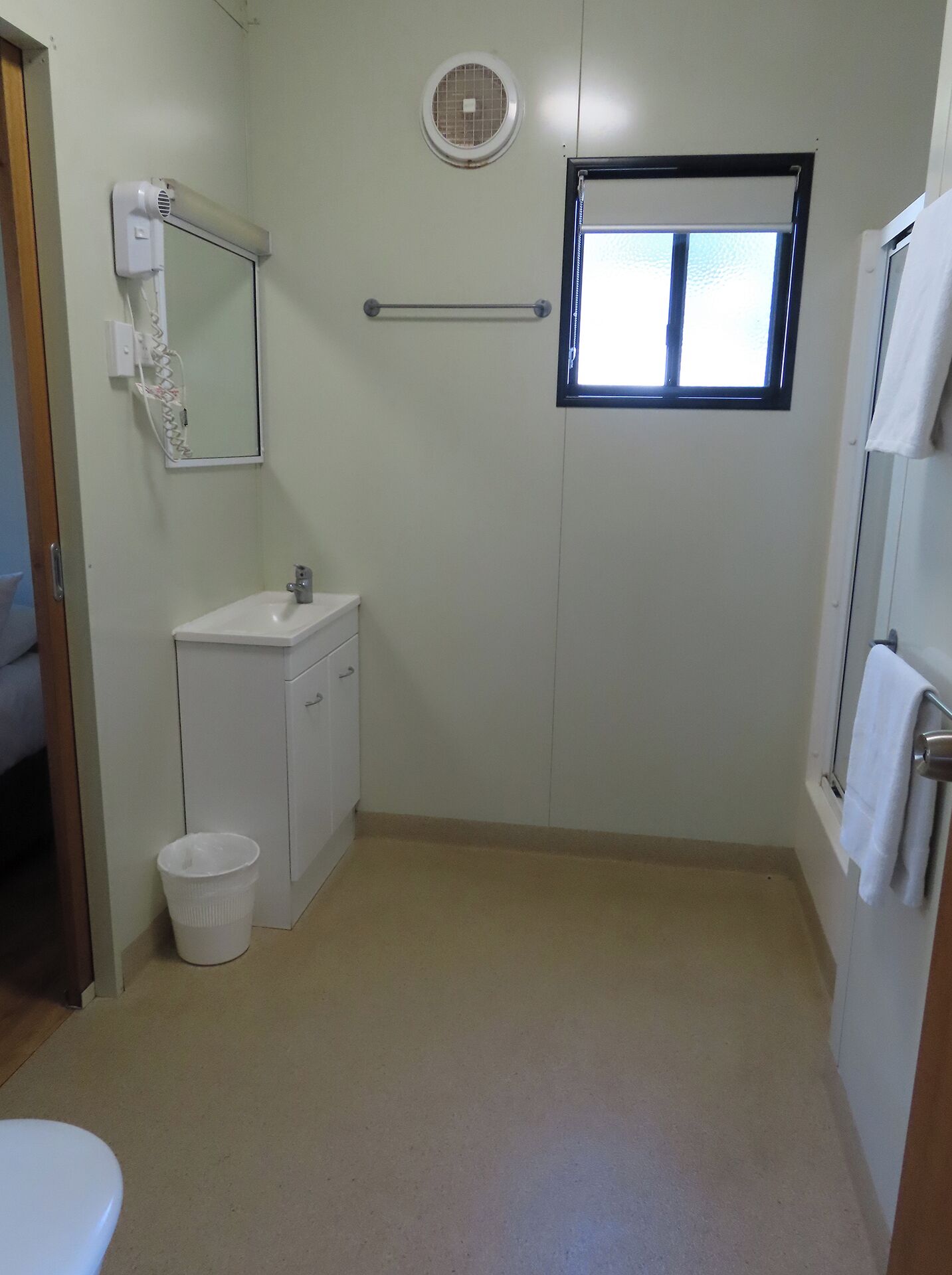 A small, clean bathroom with a toilet, sink, and window.