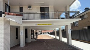 Un edificio de dos pisos con un porche cubierto, un cartel de altura libre y un patio pavimentado.