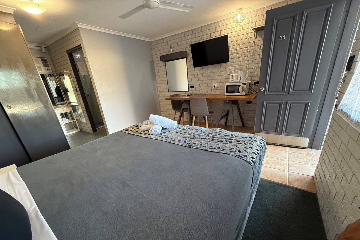 Une chambre d’hôtel avec un lit, un bureau, une télévision, un four à micro-ondes et une porte portant le numéro 31.