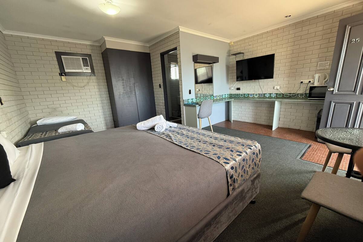 Une chambre d’hôtel équipée d’un lit, d’un bureau, d’une chaise, d’une télévision et d’une kitchenette.