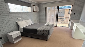 Un dormitorio con cama, mesita de noche, cómoda, ventilador de techo y vistas al exterior.