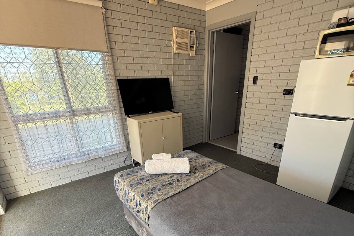 Une chambre avec un lit, une télévision, un réfrigérateur et une fenêtre donnant sur un beau paysage.