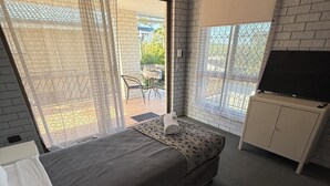 Un dormitorio con una cama, un escritorio y un televisor.