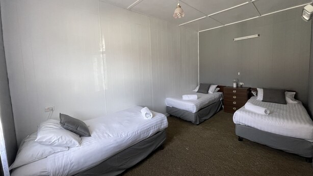 A hotel room with two single beds, a dresser, and a ceiling light fixture.