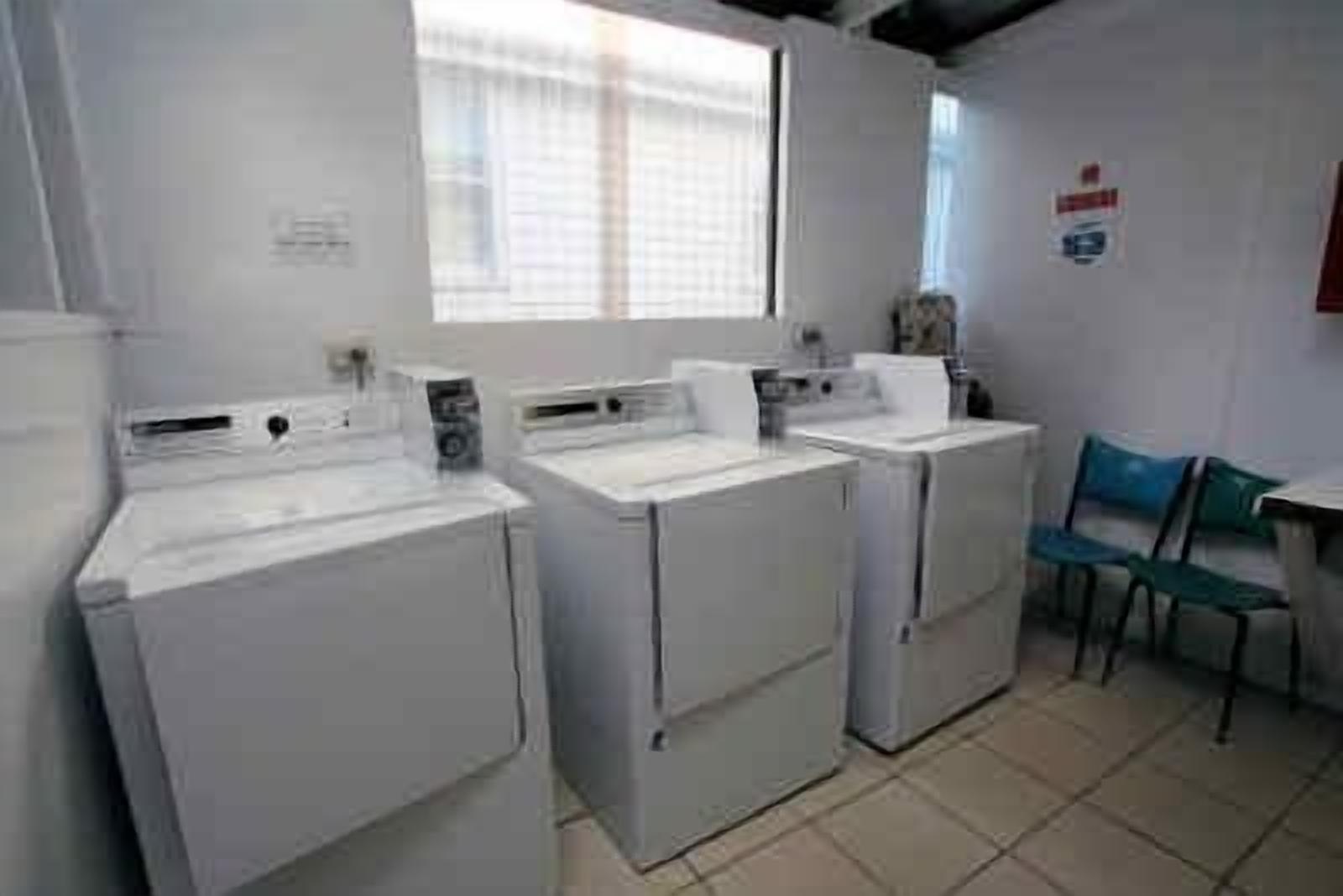 Un área de lavandería con dos lavadoras y una silla.