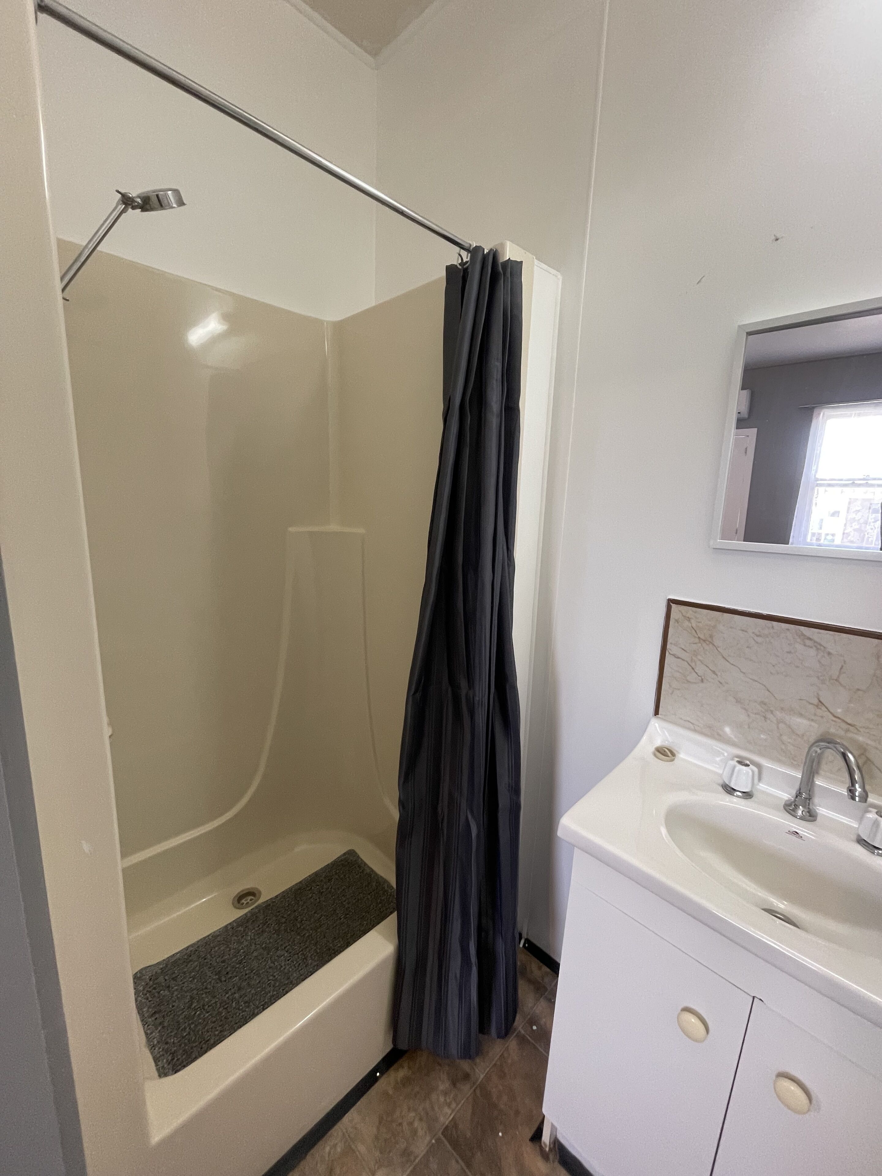 Un baño con ducha, lavabo y espejo.
