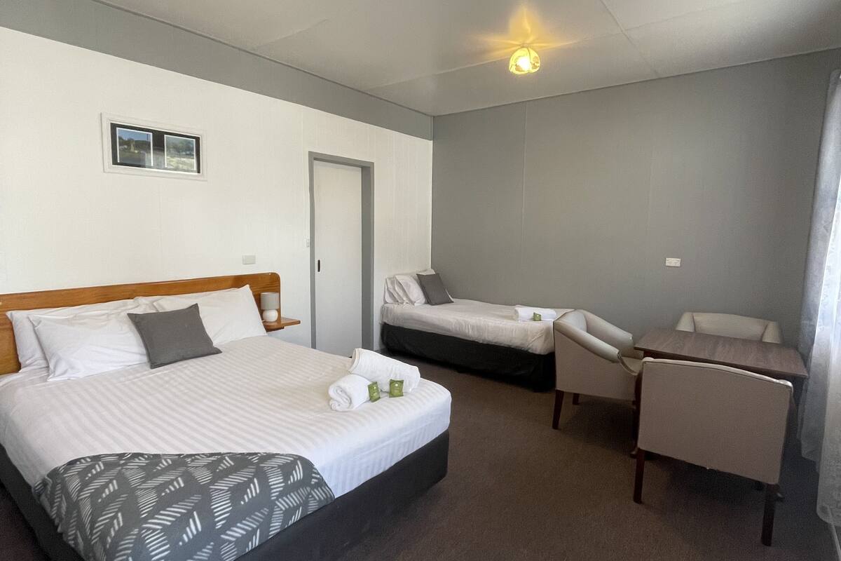A hotel room with a large bed, a smaller bed, a desk, and a chair.