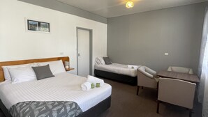 A hotel room with a large bed, a smaller bed, a desk, and a chair.