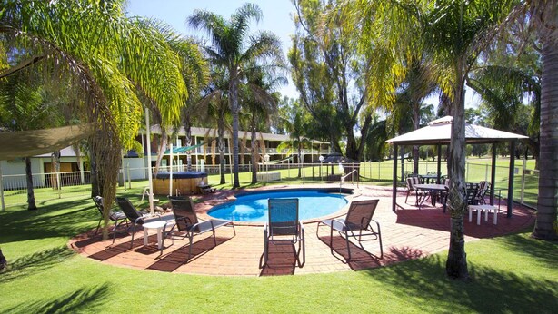 A pool area with lounge chairs, a gazebo, and a building with multiple balconies. - Tocumwal Golf Resort (Tocumwal)