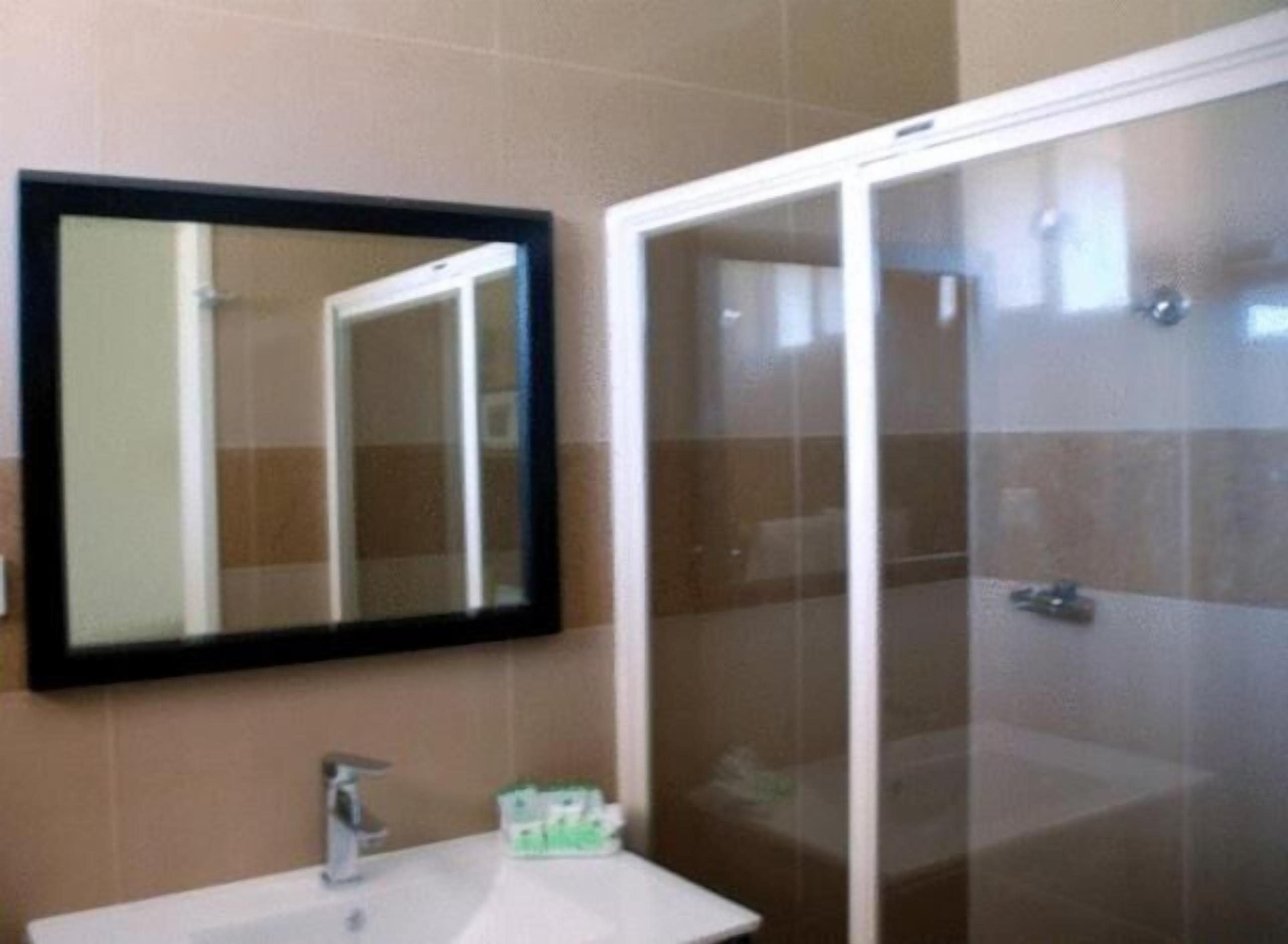 Un baño con lavamanos, espejo y cabina de ducha de vidrio.