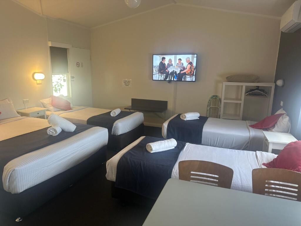 Una habitación de hotel con cuatro camas, televisión, escritorio y silla.