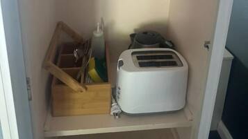 Una cocina con un tostador, una caja de madera y cristalería en los estantes.