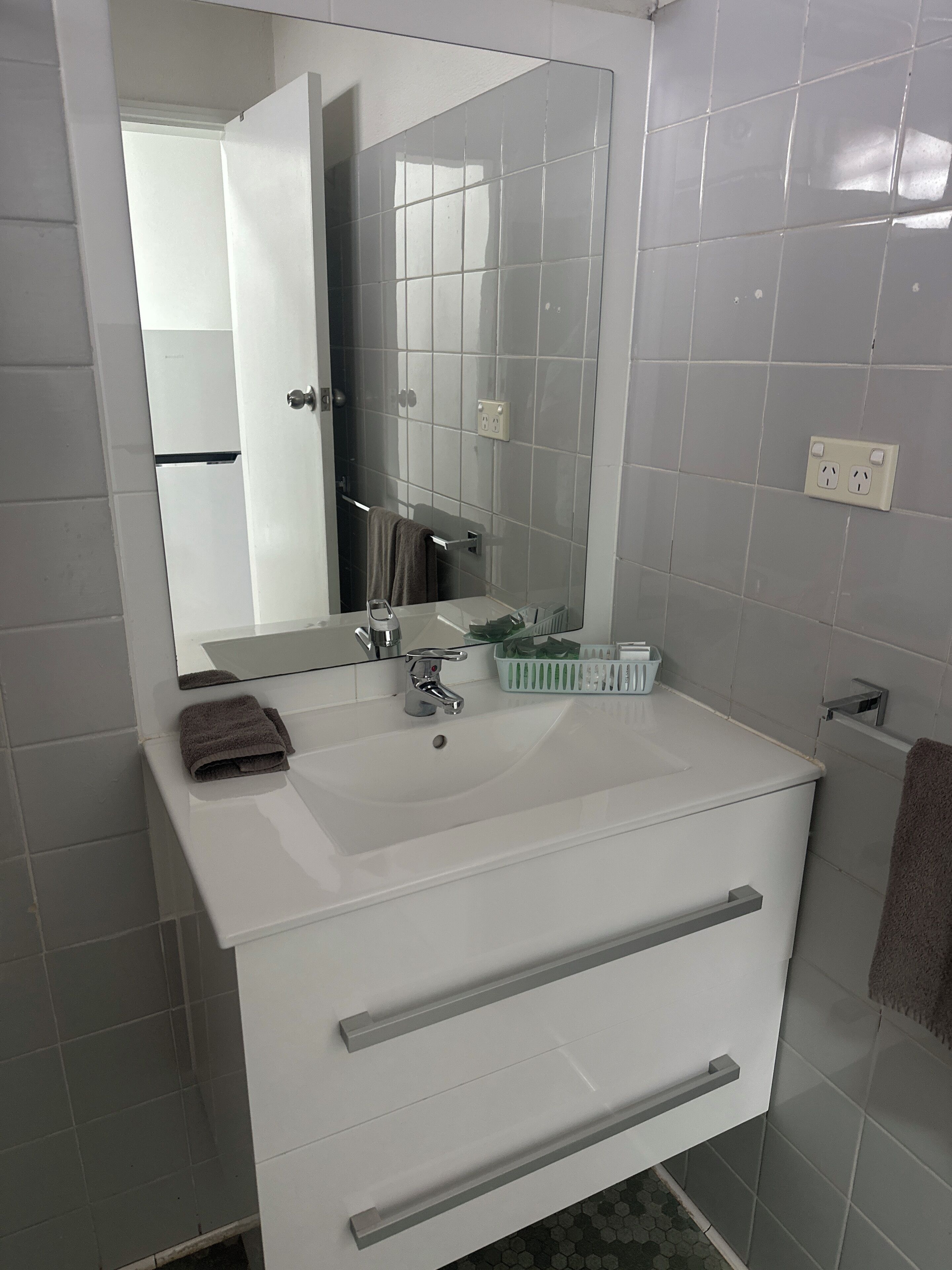 A bathroom with a white sink, a mirror, and a towel rack.