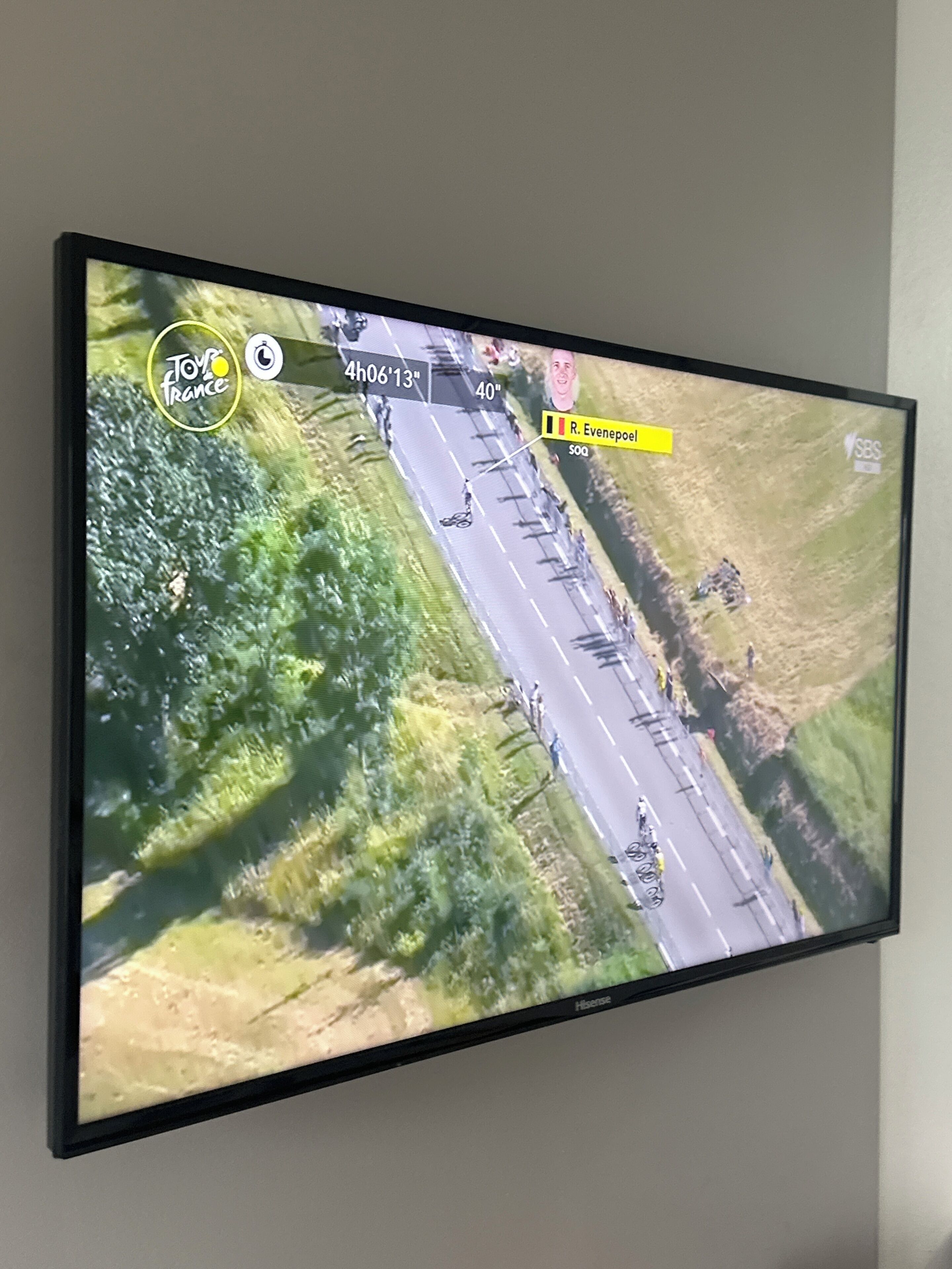 A television screen displaying a race event with a track, vehicles, and a crowd.