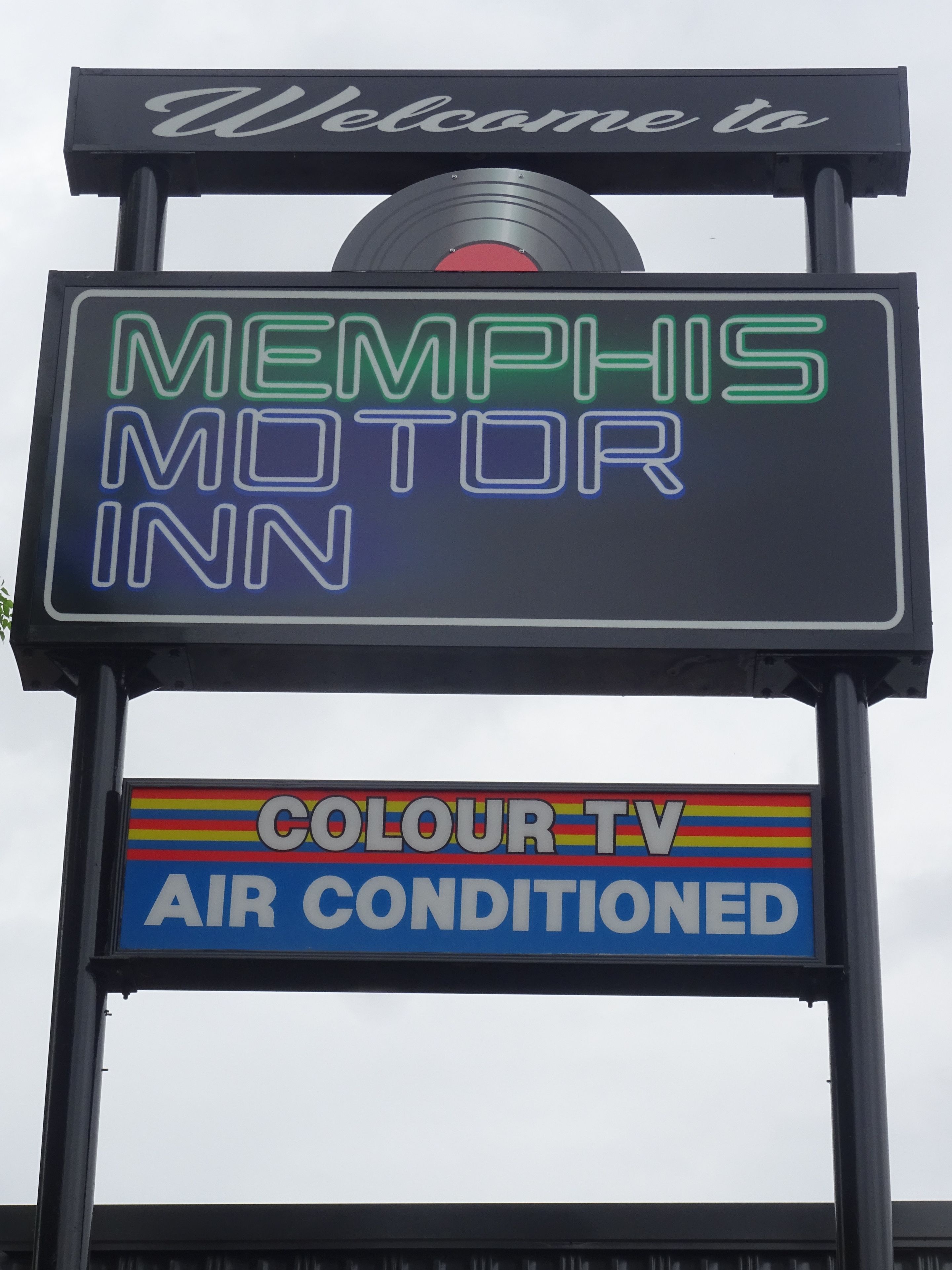 Une enseigne pour le Memphis Motor Inn, avec des néons et un disque vinyle.