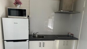A compact kitchen with a Hisense refrigerator, a microwave, a sink, and stainless steel cabinets.