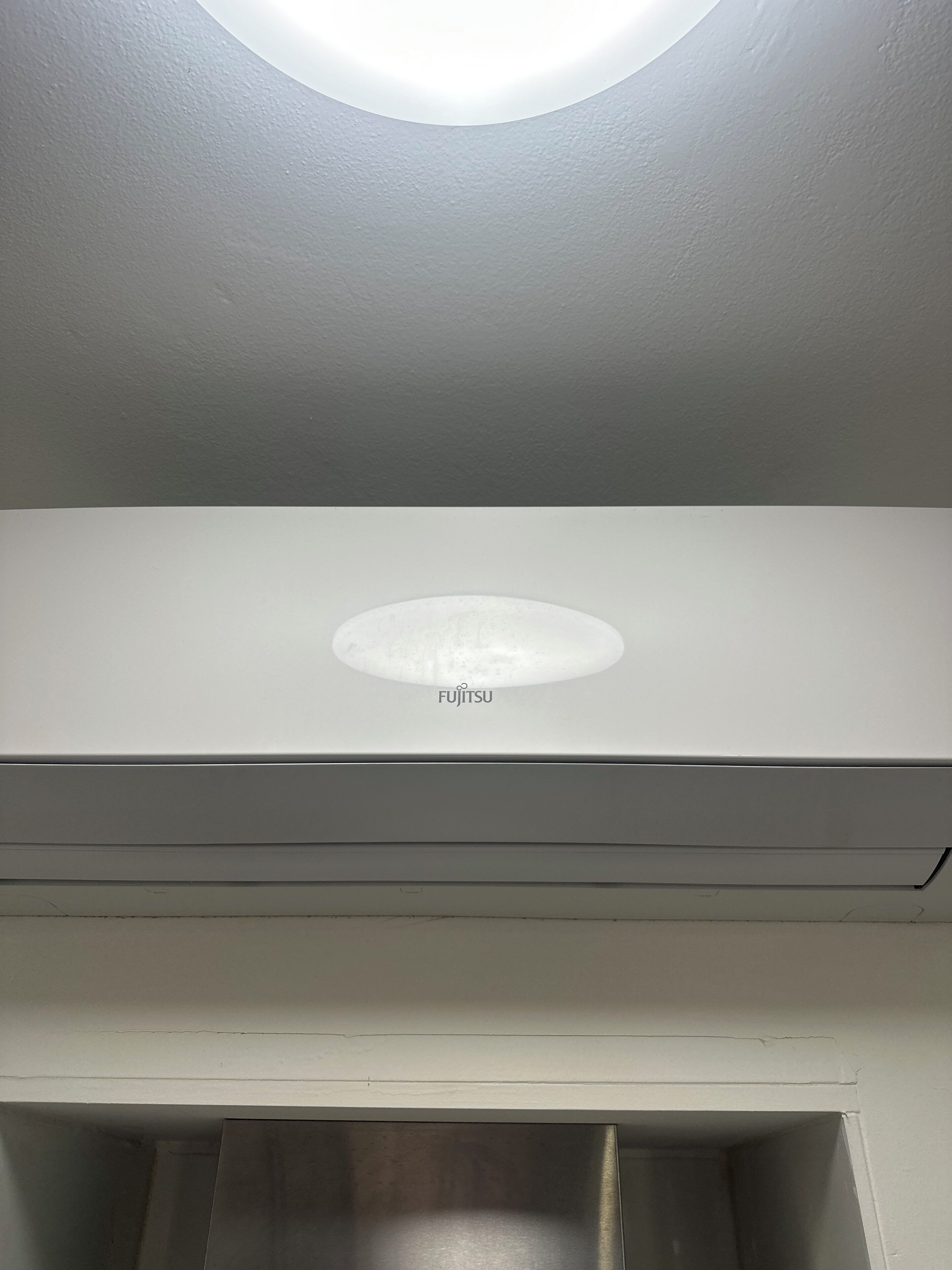 A white ceiling with a recessed light fixture and a Fujitsu logo.