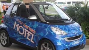 A compact car with a blue and black color scheme, featuring the text "YAMBA TWIN PINES MOTEL" on its side. - Yamba Twin Pines Motel (Yamba)