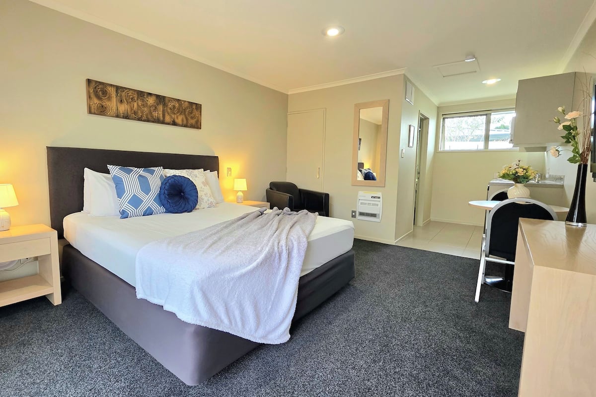 A hotel room with a large bed, bedside tables, a desk, and a mirror.