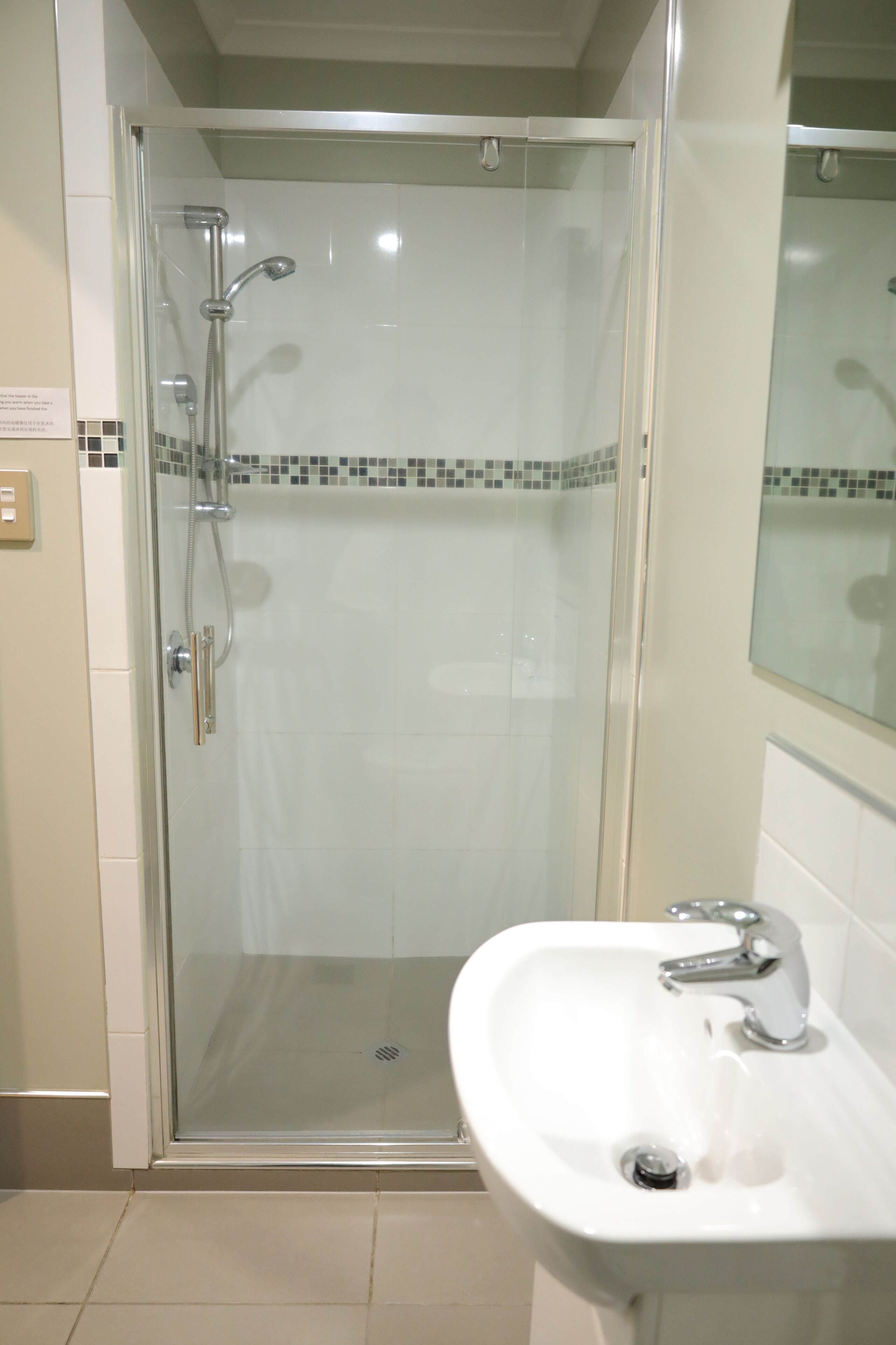 Cabina doccia in vetro con soffione a mano e rubinetto a parete.