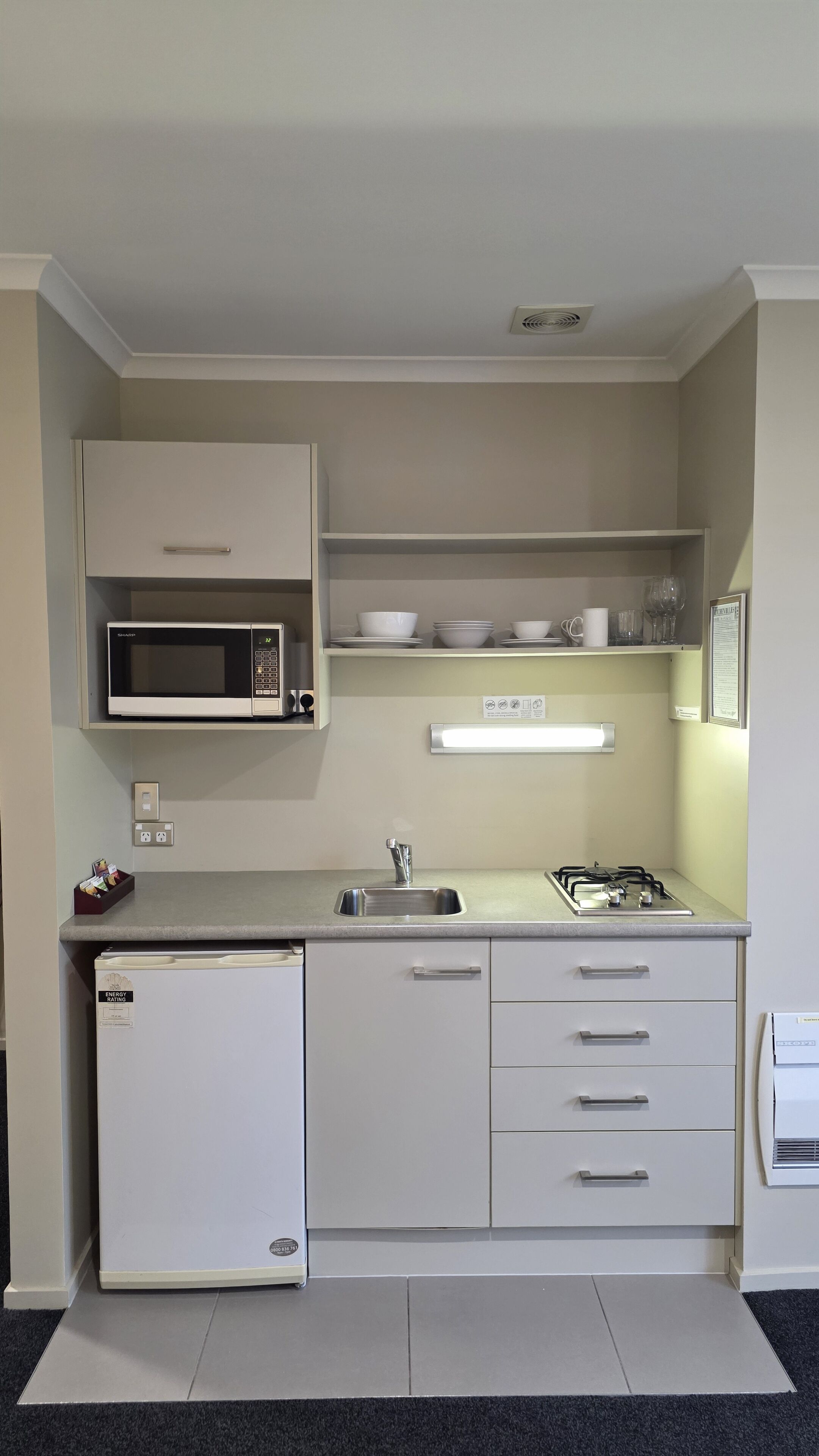 A compact kitchen with a microwave, sink, and a refrigerator.