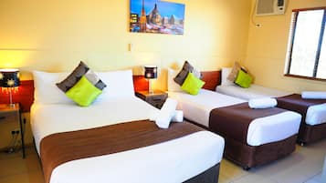 Una habitació d'hotel amb dos llits, cadascun amb un panell capçal de color marró, roba de llit blanca i coixins decoratius. Hi ha un quadre a la paret sobre els llits, i un aparell d'aire condicionat a la paret a la dreta.