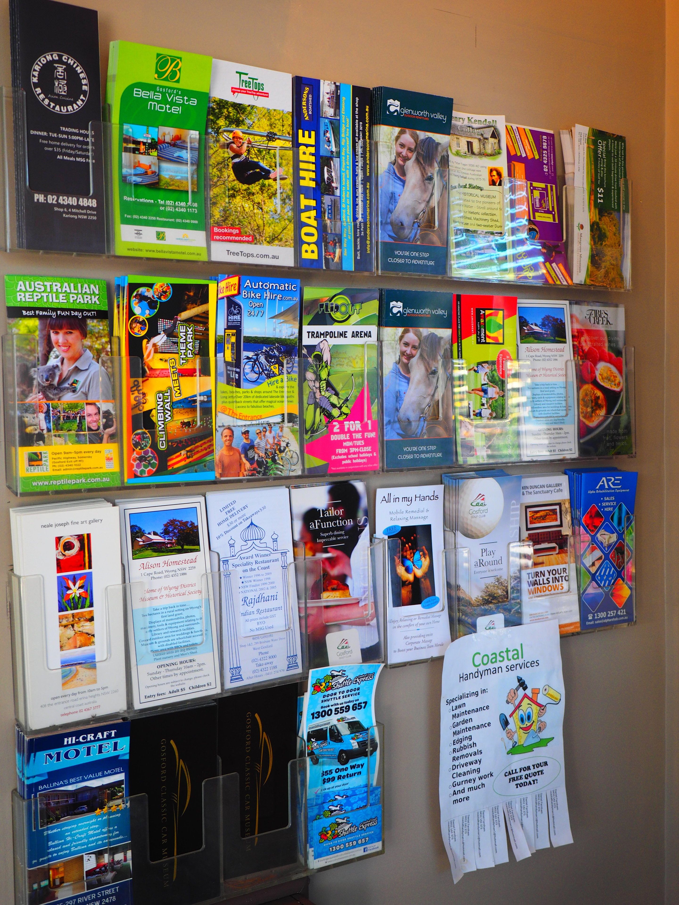 Pared con varios folletos y volantes que promocionan atracciones, servicios y alojamientos locales.