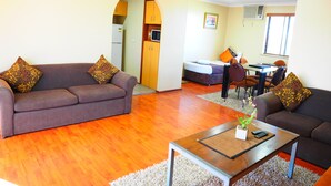 Een moderne woonkamer met een bank, salontafel en een eethoek met stoelen en een tafel.