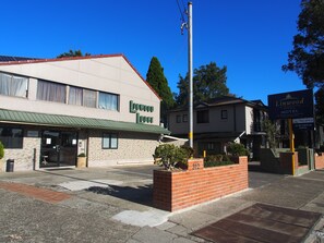 Linwood Lodge, a motel with a green awning and a brick planter with plants. - Linwood Lodge Motel (Greenwich)